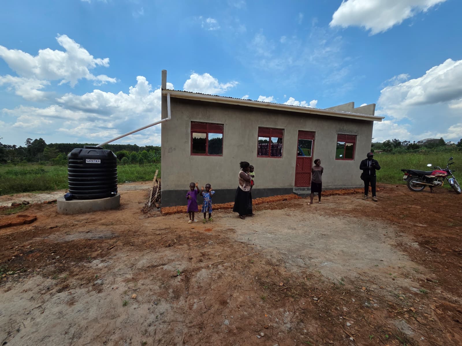 A newly built AFR home with a family standing outside in Uganda.