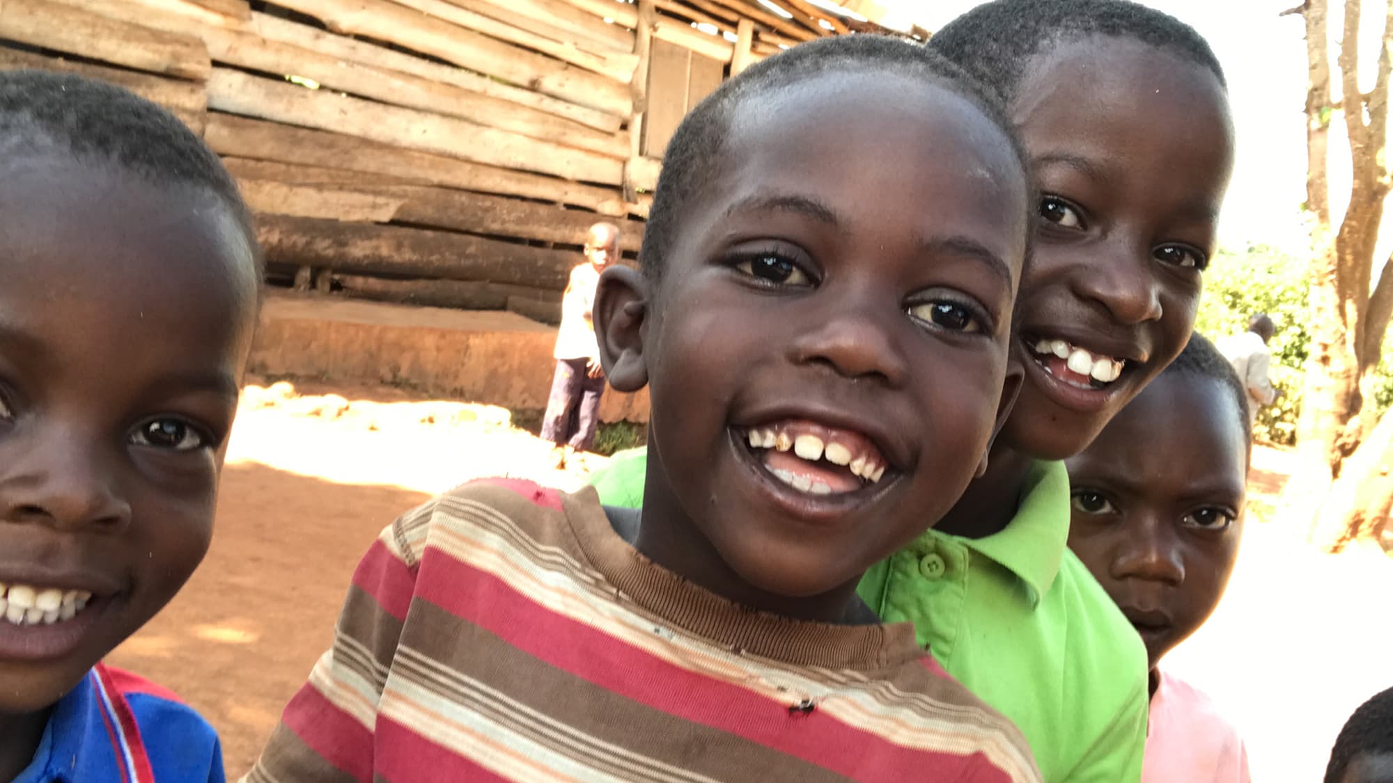 Smiling children gathered outdoors in Uganda.